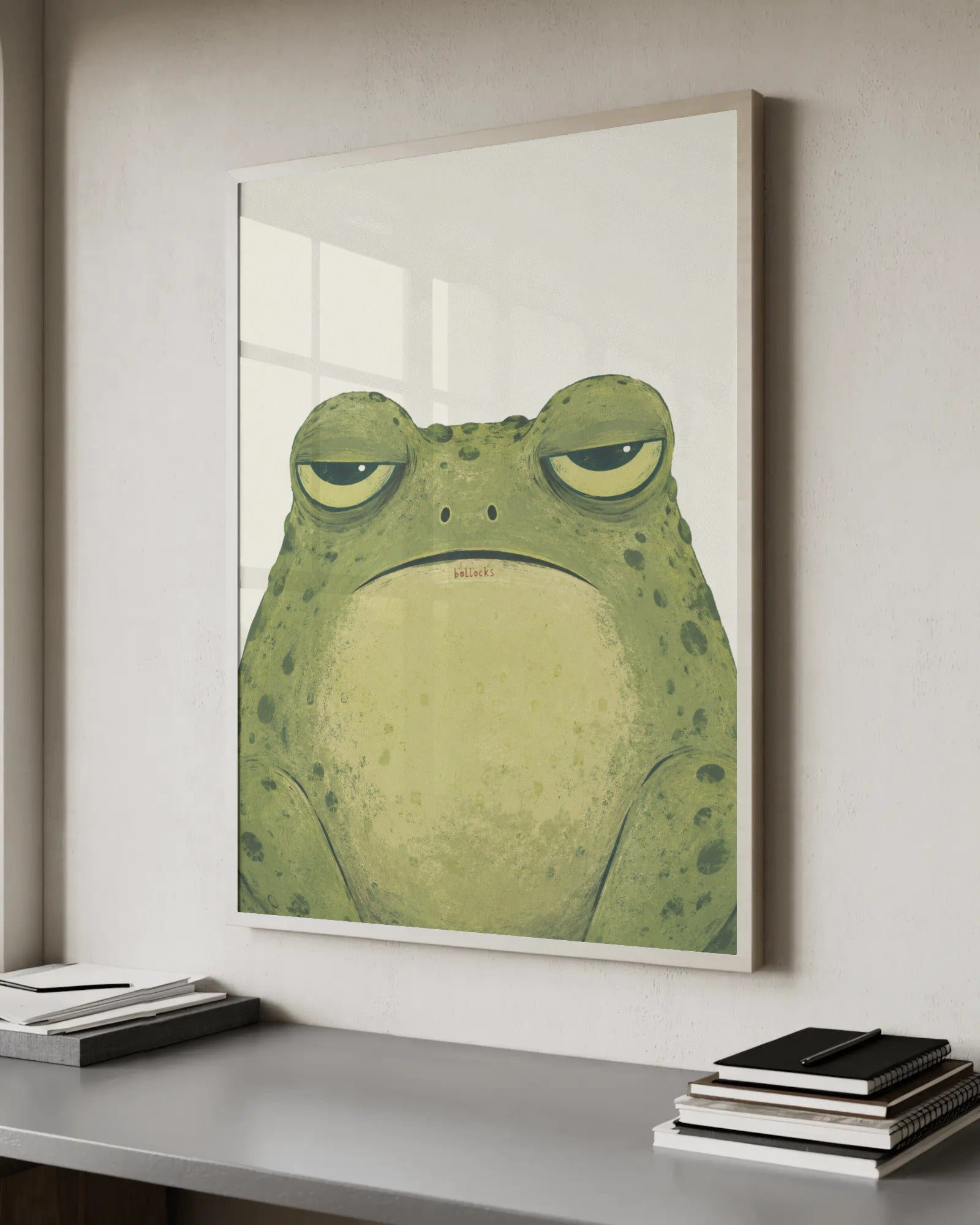 Painterly illustration of a deadpan, droopy-eyed green toad staring straight ahead, with the muttered word "b*llocks" below it, in olive green on a cream background.
